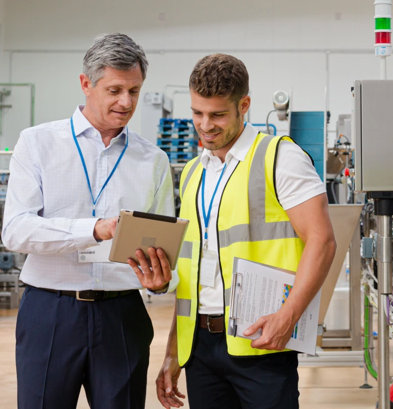 Operatorzy w hali produkcyjnej korzystają z tabletu z systemem HDF MES do monitorowania produkcji